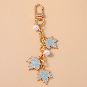 Detail of blue maple leaf charms with golden edges and pearls on a metal keychain