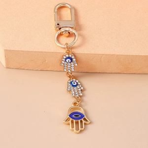Detailed close-up of golden Hamsa keychain with sparkling rhinestones and blue evil eyes