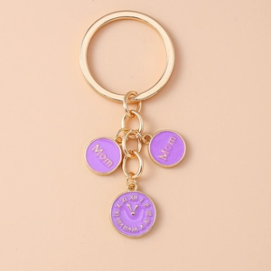Gros plan du porte-clés doré avec pendentifs violets Mom et design de cadran d'horloge