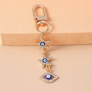 Detailed close-up of golden keychain featuring crystal starfish and evil eye charms