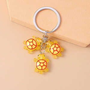 Détail de trois pendentifs tortue en résine jaune sur un anneau de porte-clés argent