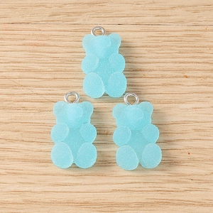 Detail of three light blue matte resin gummy bear charms with silver metal rings for DIY