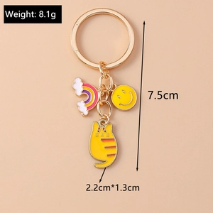 Detail view of cartoon cat keychain with rainbow and smiley face charms on gold ring