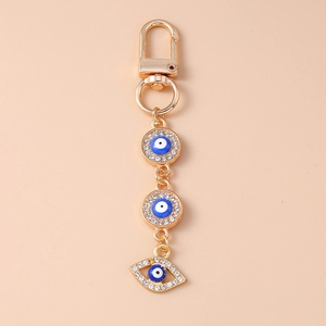 Close-up of golden Evil Eye keychain with blue enamel pendants and sparkling rhinestones