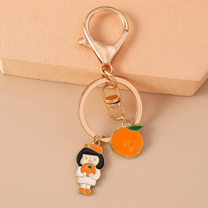 Gros plan d'un porte-clés doré avec fille en chapeau orange et breloque de fruit
