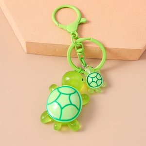 Detail of green resin mother-and-baby turtle keychain with spring hook and geometric shell pattern