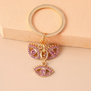 Nahaufnahme von goldenem Schlüsselanhänger mit rosa Strass-Böse-Augen-Anhängern