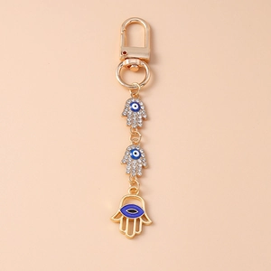 Detail of gold Hamsa hand and Evil Eye keychain charms with sparkling rhinestones