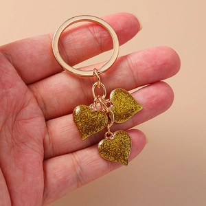 Romantic gold heart keychain with glitter sequins held in hand for backpack accessory