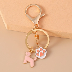 Porte-clés créatif chien et patte avec anneau en métal doré sur fond beige épuré