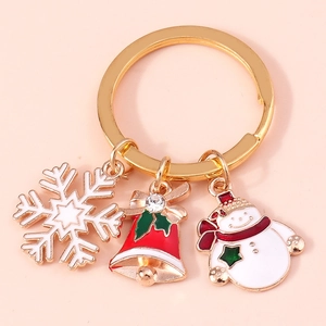 Christmas snowman and bell keychain with golden ring on a soft pink background