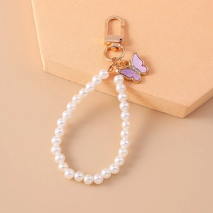 Dettaglio di portachiavi con perle e ciondolo a farfalla viola con finiture dorate