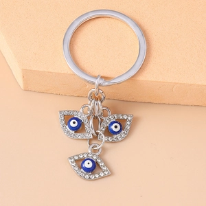 Detailaufnahme des silbernen Evil Eye Schlüsselanhängers mit blauen Kristallen und Strass