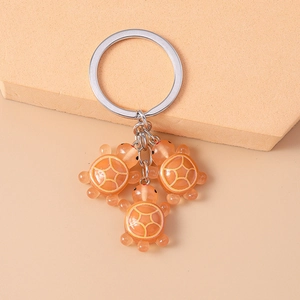 Détail de trois pendentifs tortue en résine orange avec anneau de porte-clés métallique