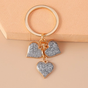 Close-up of golden keychain with three shimmering silver glitter heart pendants