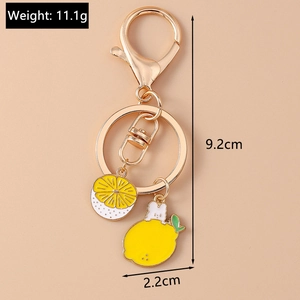 Detail of lemon and rabbit charms on a gold keychain with dimensions and weight data