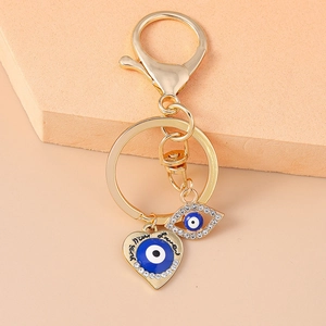 Detailaufnahme von goldenem Evil Eye Schlüsselanhänger mit Luck-Herz und blauer Emaille