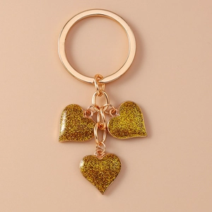 Detail of three golden heart charms with glitter finish on a metal keychain ring