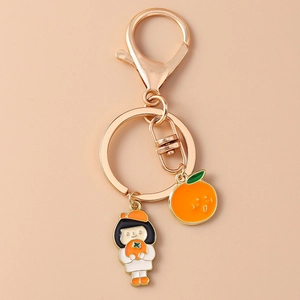 Détail du porte-clés doré avec pendentifs émaillés de fille mignonne et orange souriante