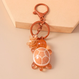 Detail of cute orange resin turtle keychain with white patterns on geometric stand