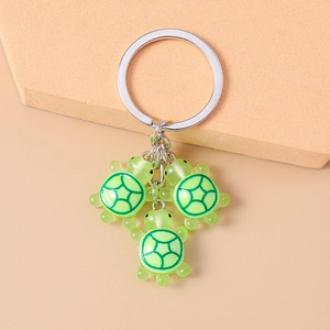 Détail de trois pendentifs tortue en résine verte avec motifs de carapace sur porte-clés
