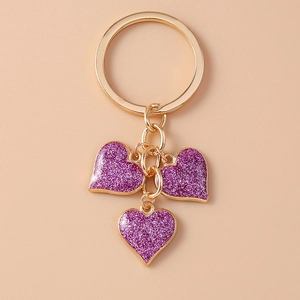 Detail of gold metal keychain with three sparkling purple heart sequins charms
