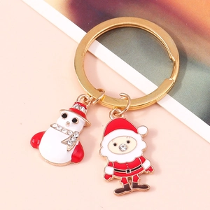 Detailed view of enamel snowman and Santa Claus pendants on a gold holiday keychain