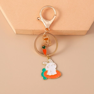 Cartoon enamel rabbit and carrot keychain with golden metal clasp on orange background
