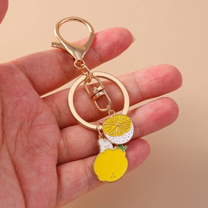 Detailed close-up of a golden lemon keychain with mini rabbit charm held by hand