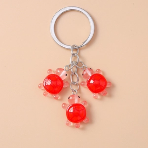 Détail de pendentifs tortue en résine rouge avec chaîne métallique polie sur porte-clés