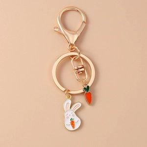 Detail shot of golden metal lobster clasp with cartoon white rabbit and carrot charms