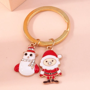 Detailed close-up of a festive enamel Christmas snowman and Santa Claus keychain with rhinestones