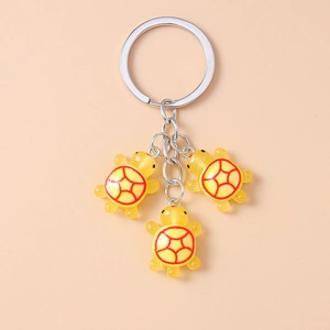 Détails de trois pendentifs tortue en résine jaune avec motifs rouges sur anneaux métalliques