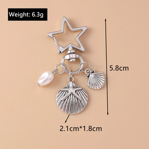 Detailed view of silver starfish and shell charms with a pearl on a star-shaped keyring