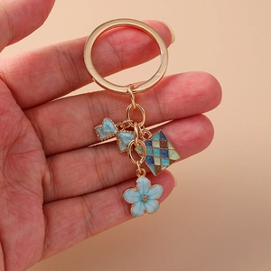 Portachiavi dorato con fiocco in smalto blu e ciondoli a fiori di ciliegio
