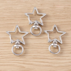Three silver star-shaped lobster clasps with rotating rings on a wooden background