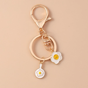 Close-up of a cute fried egg keychain with golden lobster clasp and enamel pendant
