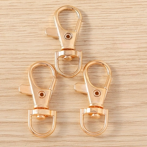 Close-up of three gold-plated star-shaped lobster clasps on a light wood surface
