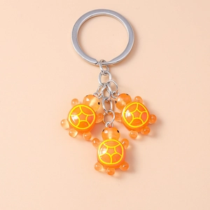 Vue détaillée de trois tortues en résine orange avec motifs géométriques jaunes sur la coque