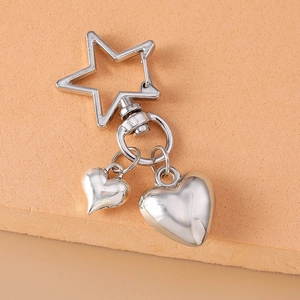 Silver starfish and heart keychain with polished metallic finish on a warm pedestal