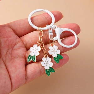 Sweet cherry blossom keychain with white enamel petals and golden accents on a metal chain