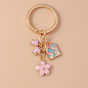 Dettaglio portachiavi dorato con fiocco rosa, fiore e ciondoli in smalto raffinati