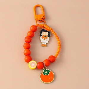 Detailed macro view of orange beaded keychain with cute girl and persimmon charms