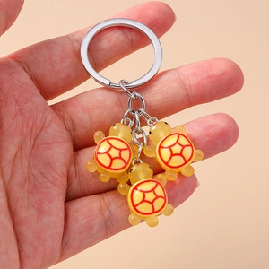 Vue de trois porte-clés tortue mignons en résine jaune avec des motifs colorés en main