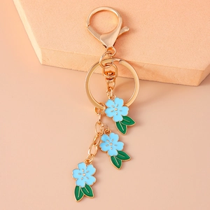 Detailed macro view of gold lobster clasp and light blue enamel flower pendant charms