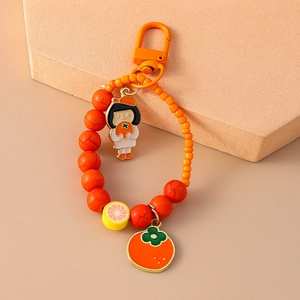 Detail of orange beaded keychain with cute girl charm and simulation fruit pendants