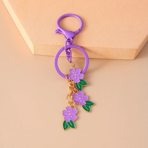 Detailed view of purple cherry blossom keychain with three floral charms and golden hardware