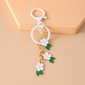 Detail of white cherry blossom keychain with green leaves and white lobster clasp