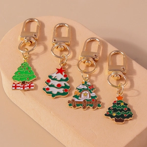 Detail of four colorful Christmas tree keychains with golden metal D-rings on a beige stand