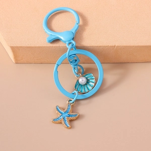 Detail of a blue ocean-themed keychain featuring a pearl shell and starfish charm